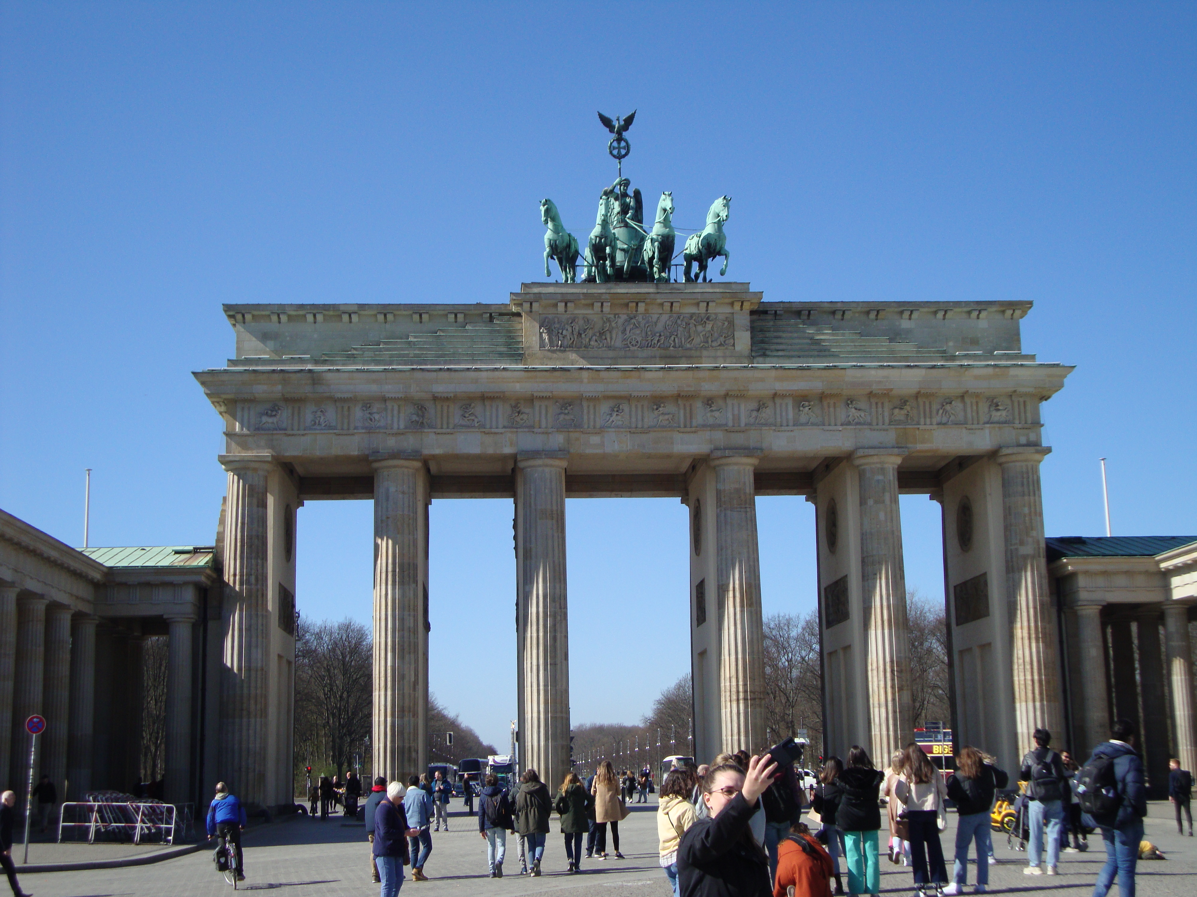  a large stone structure with columns and statues on top with Brandenburg Gate in the background